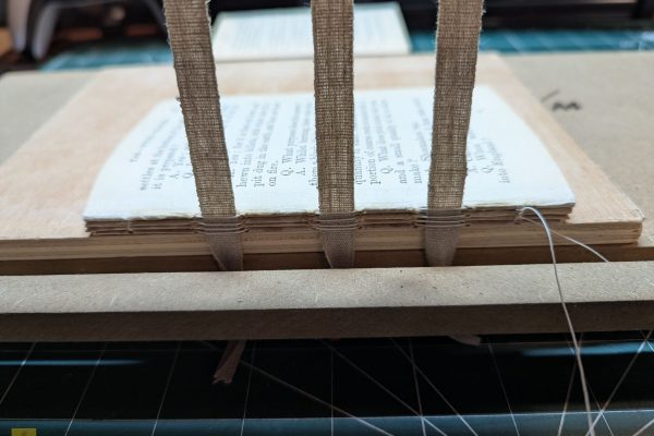 Sewing the signatures together with the sewing tapes.