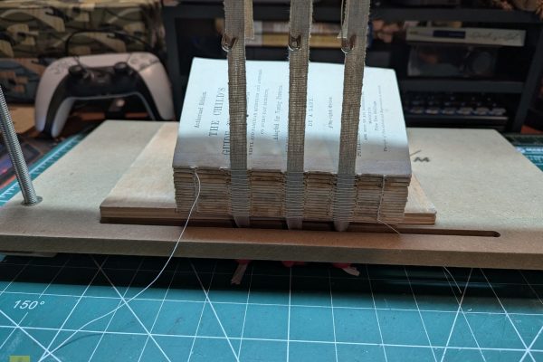 Sewing the signatures together with the sewing tapes.