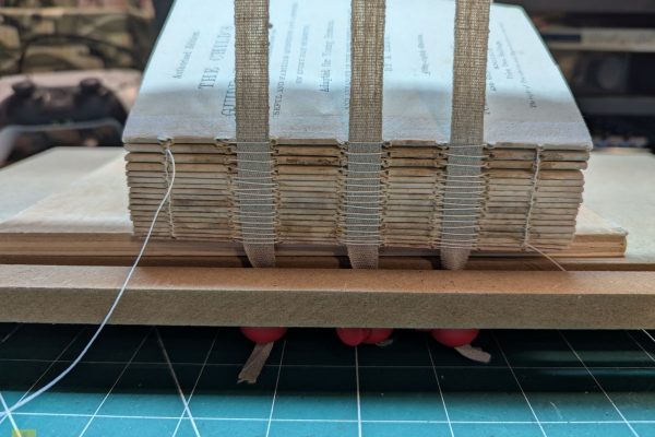 Sewing the signatures together with the sewing tapes.