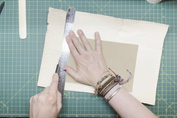 Trimming a ruler's width from the edge of the card.