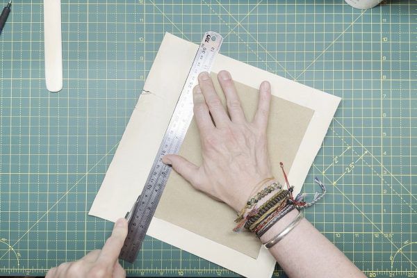 Trimming a ruler's width from the edge of the card.